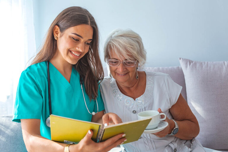 Young,Caregiver,And,Senior,Woman,Laughing,Together,While,Sitting,On