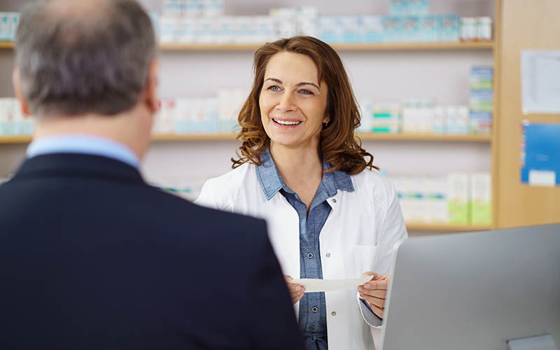 Woman,Pharmacist,Helping,A,Male,Customer,Dispensing,His,Prescription,Medicine